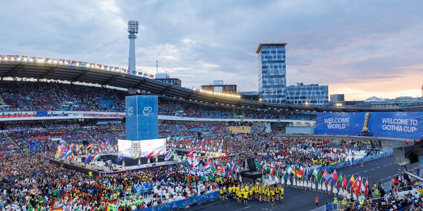 The Gothia Cup opening ceremony at dusk in Ullevi Stadium — the stands full, teams and flag bearers gathered on the ground below.